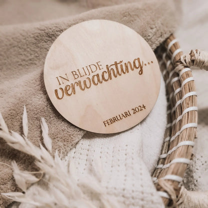 Houten aankondigingsbordje voor een zwangerschap, gegraveerd met de tekst "In blijde verwachting" en de uitgerekende datum.